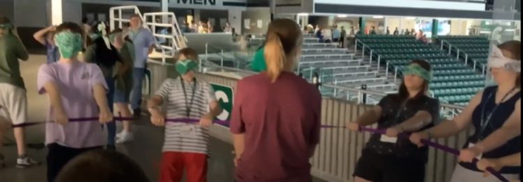 Blind folded youth in a circle holding on to a rope.