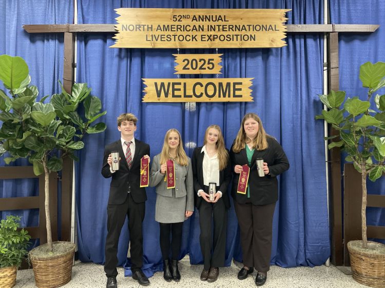 Four youth holding up their ribbons in front the NAILE sign.