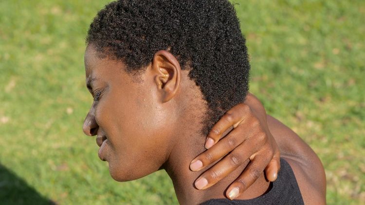 A young person holding their neck in pain.