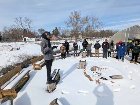 About 15 people listening to a farmer during a winter farm tour.