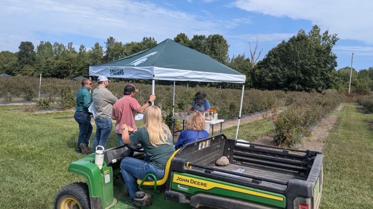 people standing by a green implement and a tent