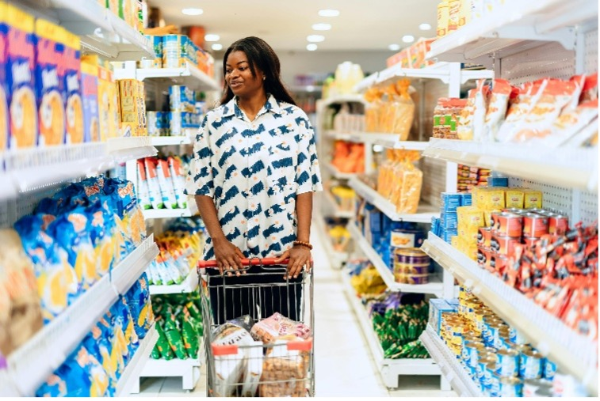A person pushes a cart down a grocery store aisle.