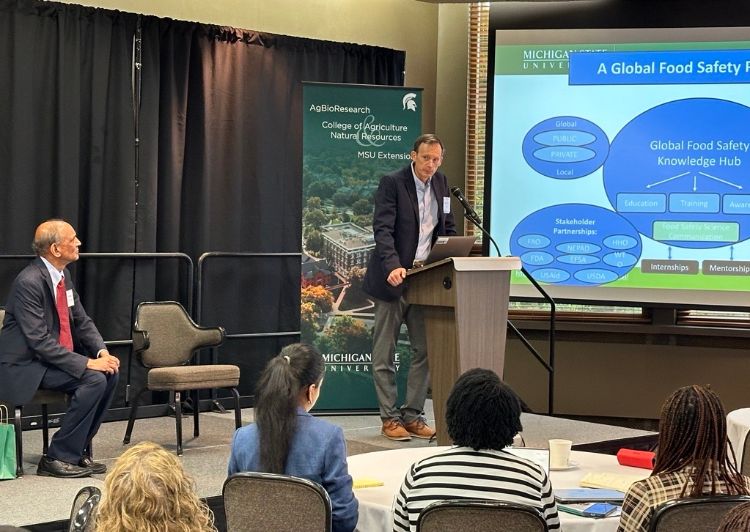 Matthew Daum speaks at a podium, engaging a group of attendees during his presentation on stage