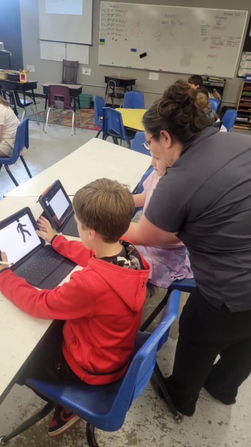 A woman standing over two kids with iPads.