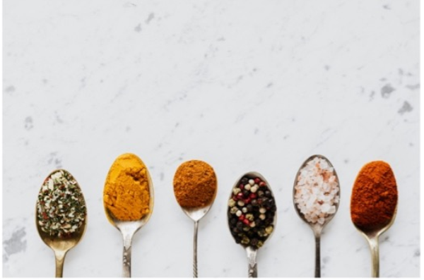 A photo of a row of spoons with different spices