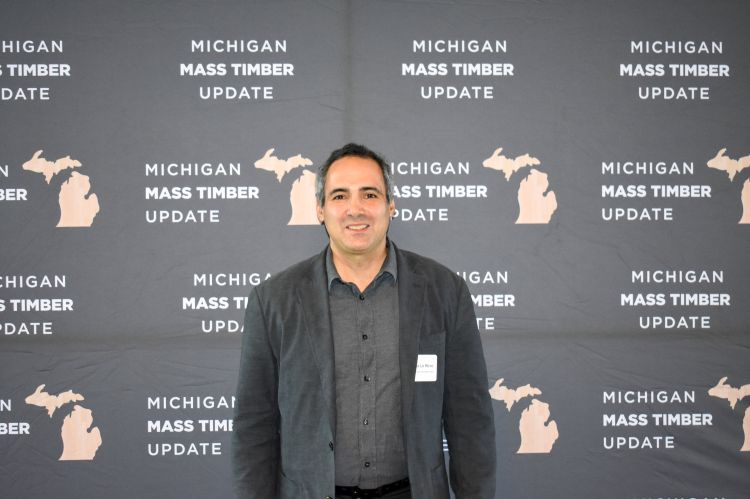 Marco Lo Ricco, Research General Engineer, USDA, Forest Service, Forest Products Laboratory, posing for a picture behind a media banner displaying 