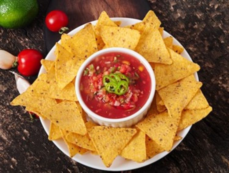 a plate of tortilla chips with a bowl of salsa in the middle.