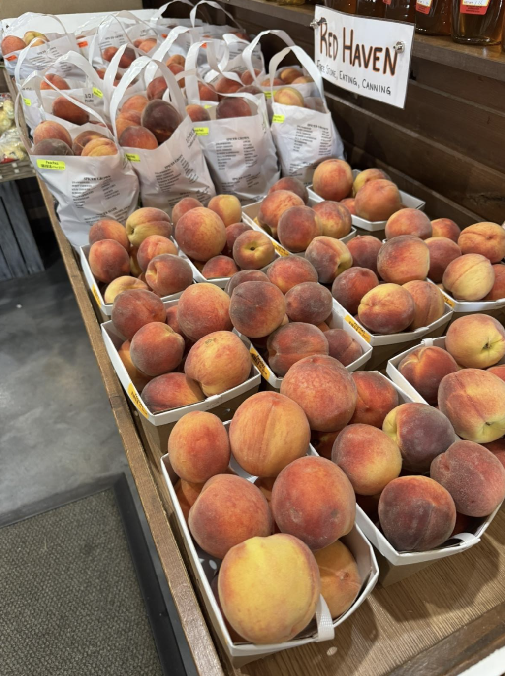 A photo of peaches in white bags at a farm stand.