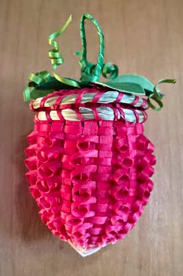  Bright pink woven ash basket shaped like a strawberry with green decorative leaves and hanging loop.