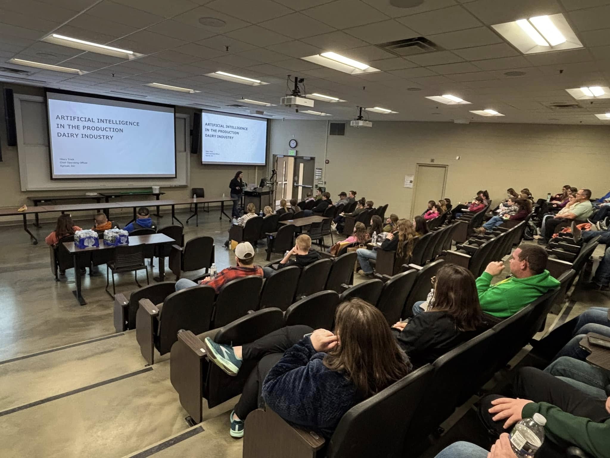 A group of youth in a large classroom with a powerpoint on the projector screen.