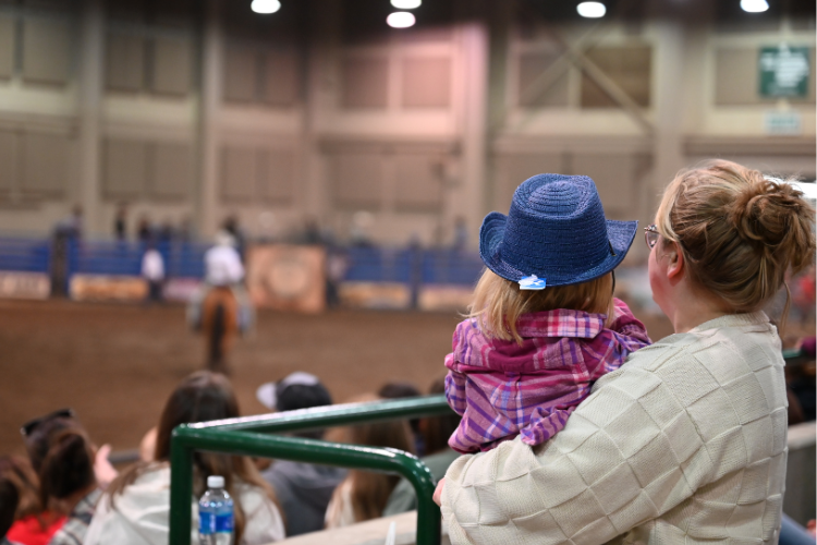 Image of a young fan at the rodeo wearing a cowboy hat.