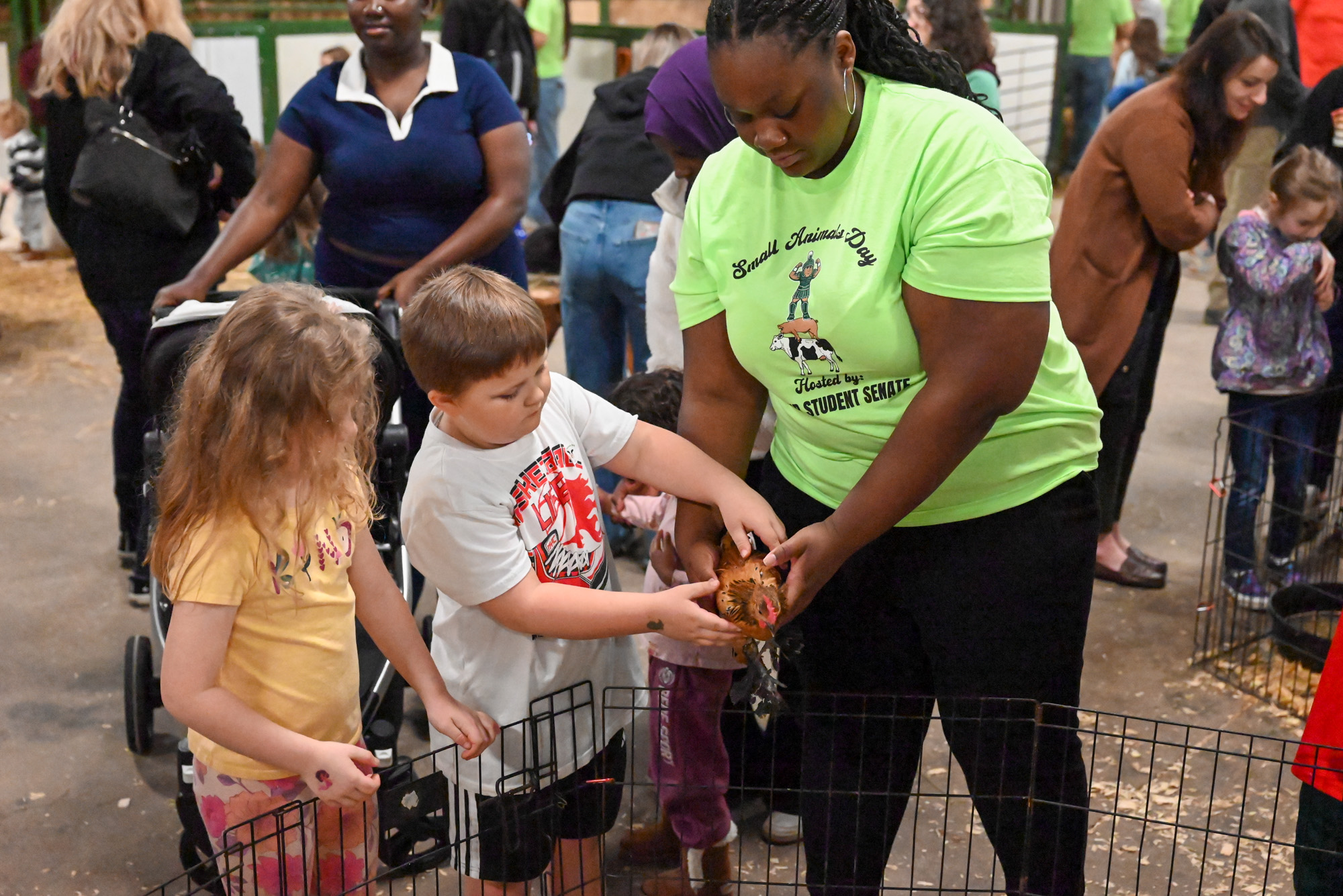 An MSU student shows two children how to hold a chicken.
