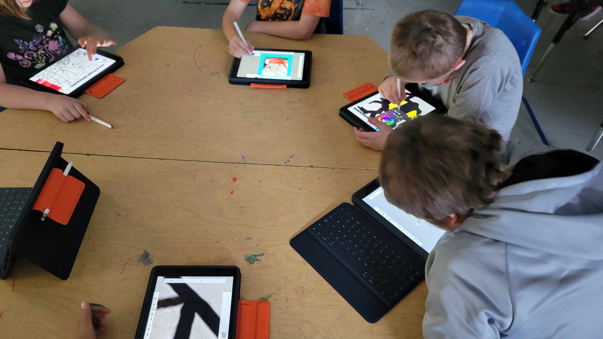 youth sitting around a desk on iPads.