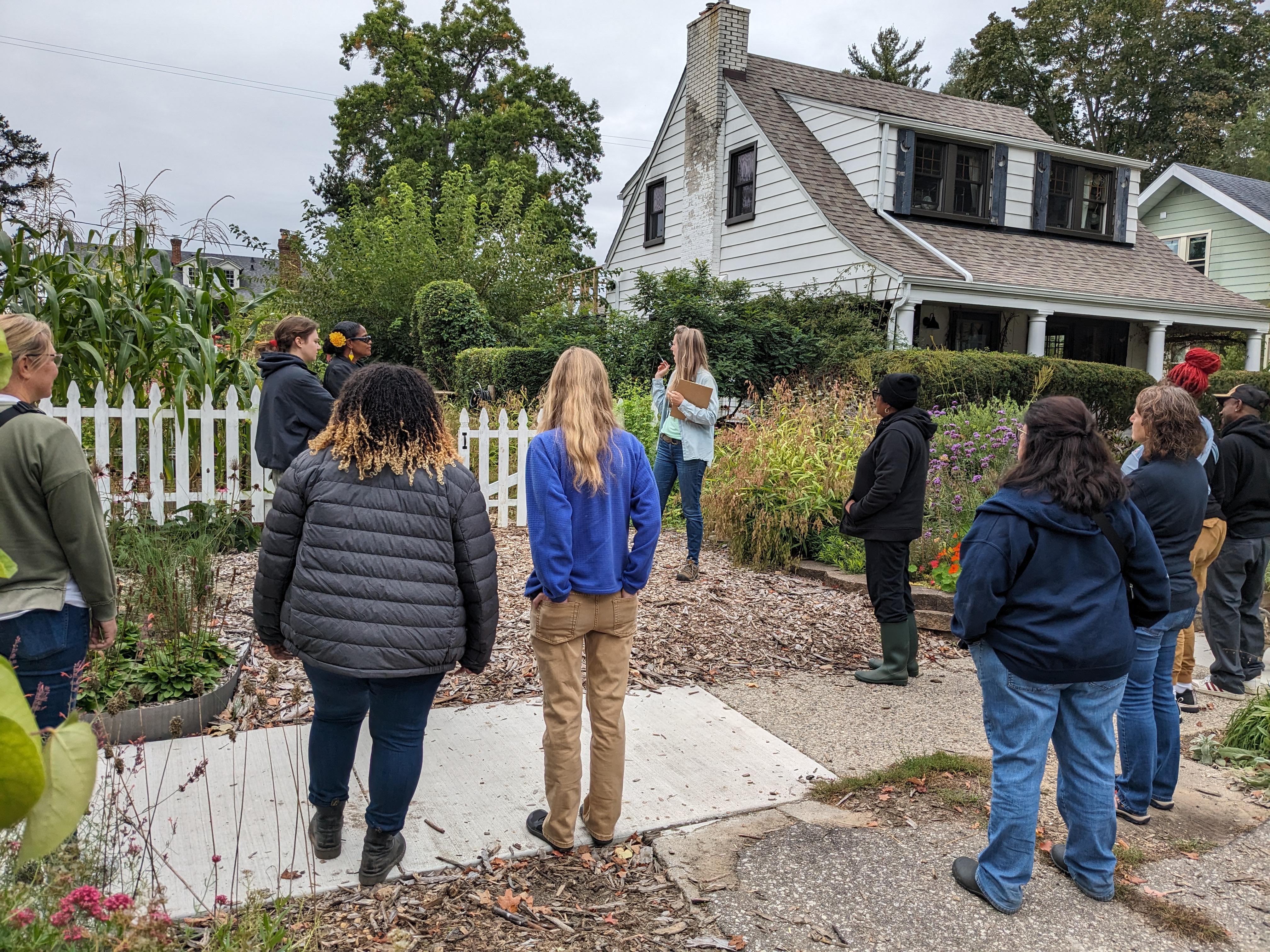 A woman leading a tour of her Flint flower farm with her home in the background