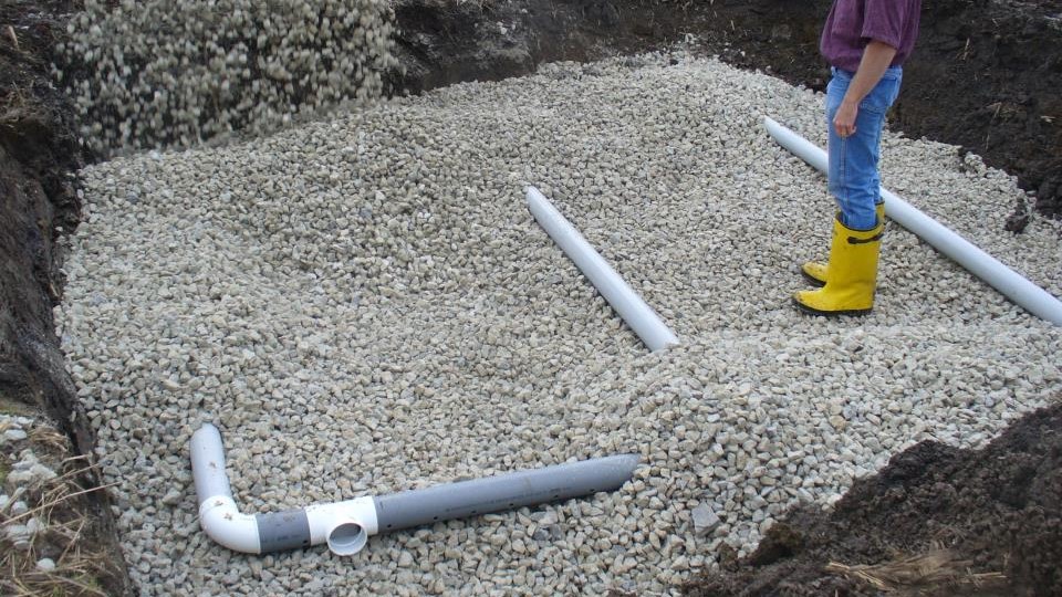 Coarse gravel being poured over the perforated collection pipe