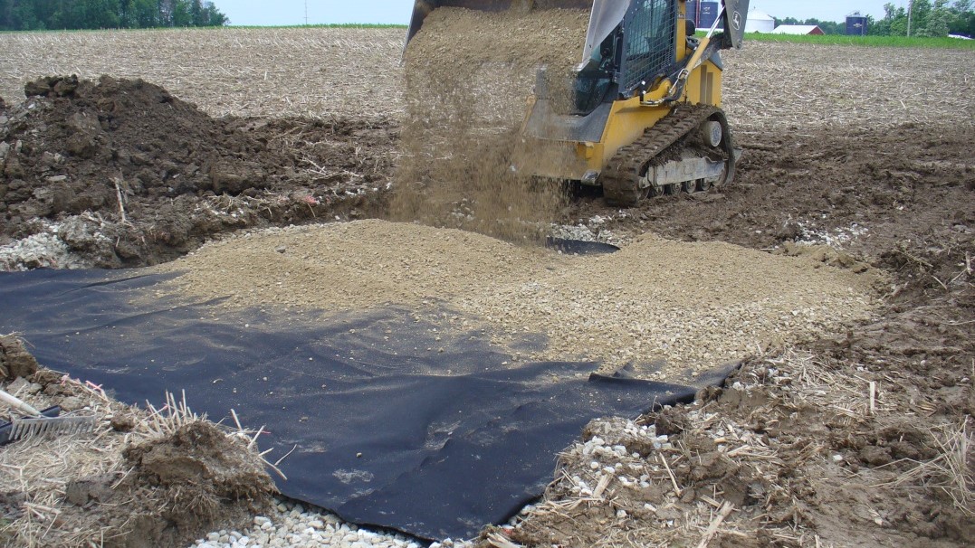 Sand being poured over the nonwoven geotextile fabric